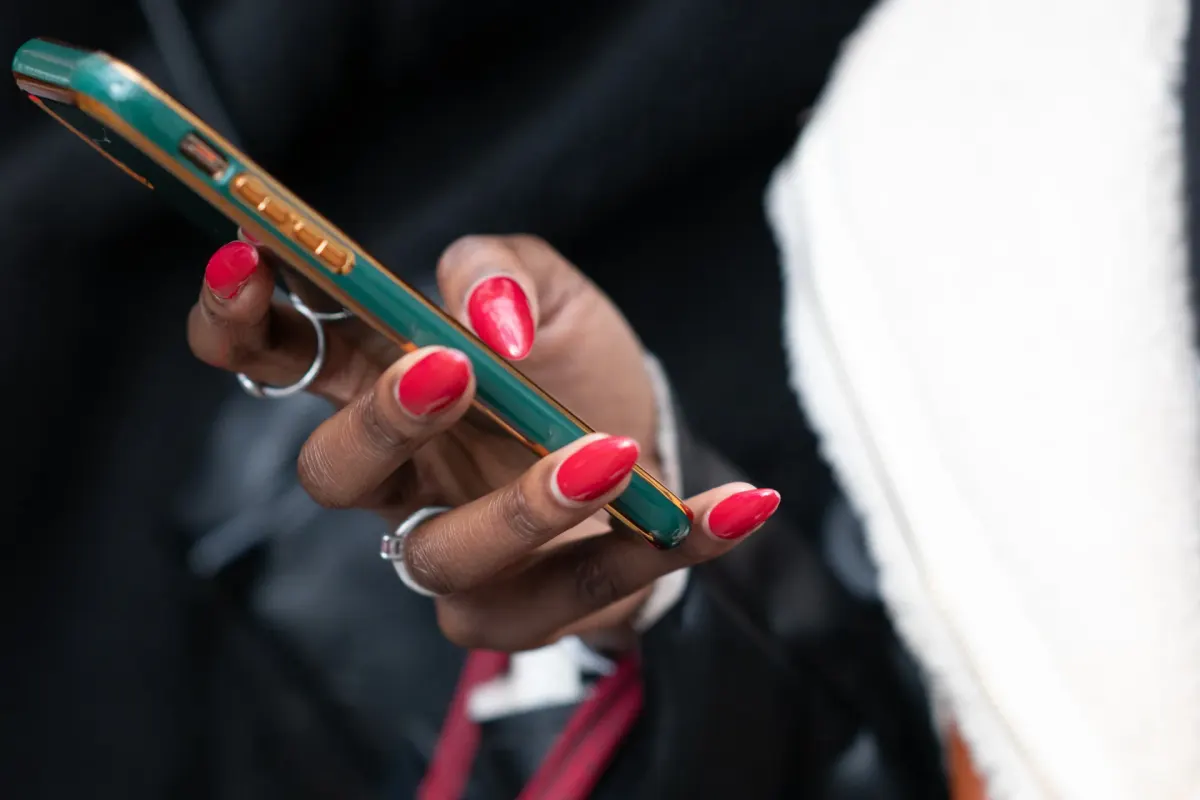 Hand with red nails holding a green smartphone